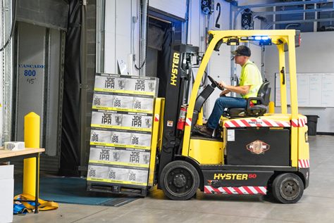 A man driving a forklift lifting a box
